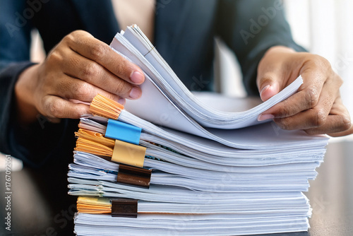 Hands sorting and organizing a large stack of business documents with colored clips