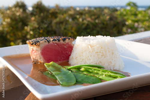 Sesame-crusted tuna steak in a ginger sauce with snow peas and white rice. Fine dining plate at a restaurant in Turks and Caicos. 