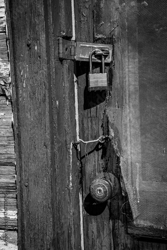 A series of latches and locks on a weathered and worn door.