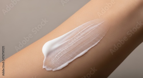 Closeup of white cream being applied to a persons arm, showcasing texture and skin care