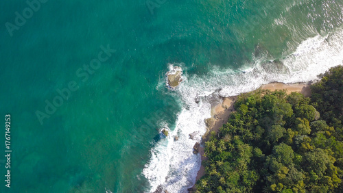 Vista del mar con olas rompiendo en las rocas y una isla bajo el cielo de verano