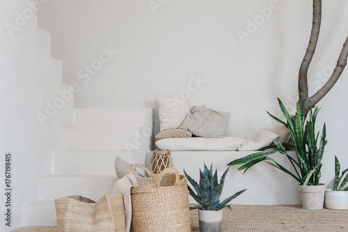 Beautiful handcrafted jute baskets standing on a soft rug near lush green plants. Natural home decoration in boho and eco style. Warm light, neutral colors and textures create a calm and cozy interior