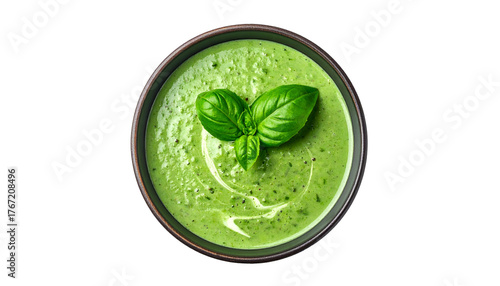 Overhead shot of a creamy green soup, garnished with fresh basil leaves, in a dark bowl
