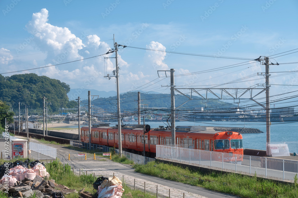 Naklejka premium Orange Iyotetsu Train at the seaside station, Baishinji Station, Matsuyama, Ehime, Shikoku, Japan