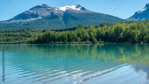 Turquoise lake reflects snow-capped mountain and lush green forest