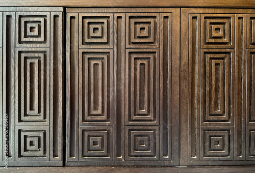 Detail of geometric rectangular pattern carving on a dark wood surface. Antique retro concept. For carpentry, doors, and wall panel. Modern vintage classic feel. Seamless background texture.