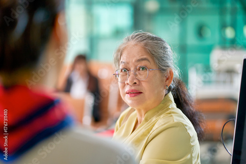 Senior woman passenger face at airport check in counter service with air ground staff foreground , Travel by airplane service.