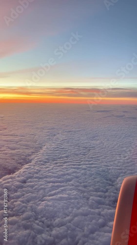 Sunset over a sea of clouds, from an airplane perspective, and with a small part of the engine visible, portrait mode