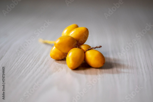 yellow plums on wooden table, bunch of ripe date palm fruits (phoenix dactylifera) isolated on white table close up