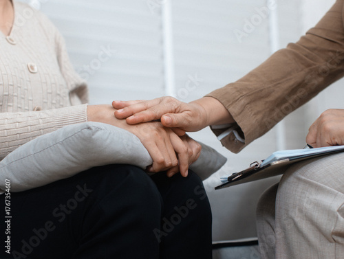 Close-up of Asian female Psychologist holding her patient hand listening, empathy during consultation and Mental health Therapy session in clinic. Psychologist supporting her patient in office.