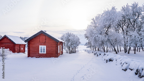 Farm barn and house in a cold winter landscape with snow and frost.