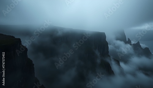 Misty mountain peaks shrouded in dense fog, creating a dramatic and atmospheric landscape with sharp cliffs.