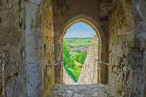 Interior of old arched doorway within ruins of medieval anglo-saxon motte-and-bailey castle showing view over rural countryside landscape
