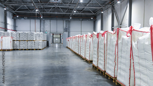 Large stacks of white bags, neatly stacked on wooden pallets and wrapped in transparent plastic.