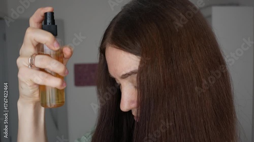 Hair growth stimulation procedure. A woman applies a natural herbal remedy to her scalp. Anti-hair loss spray. A procedure to restore hair growth in a patient.
