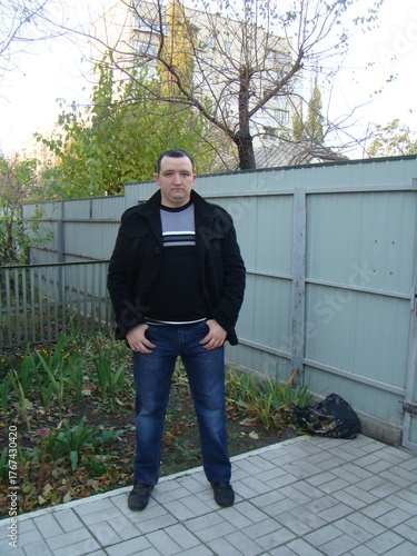 portrait of a young man. man in a coat.Casual portrait of a man standing outdoors near a fence on an autumn day. Natural light