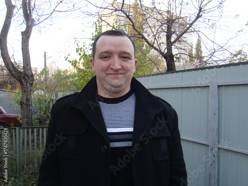 portrait of a young man. man in a coat.Casual portrait of a man standing outdoors near a fence on an autumn day. Natural light