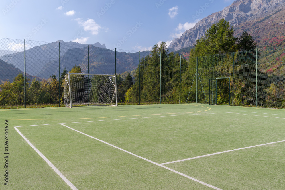 Fototapeta premium Football field with forest and mountain in back, Alps, Italy