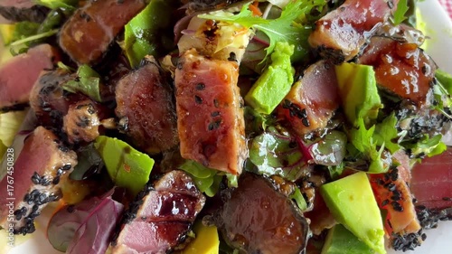 Tuna steak salad featuring with avocado, black sesame, arugula, basil and sauce. A culinary delight.