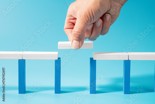 Hand builds a wooden toy bridge symbolizing trust and connection