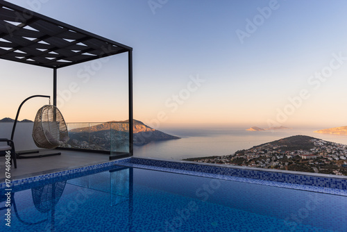 A tranquil rooftop pool overlooks a coastal town and distant islands