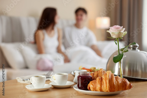 Φωτογραφία Delicious breakfast served on wooden table and couple staying in bed at hotel ro