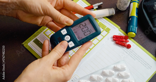 A woman examines her elevated blood sugar reading on a glucometer at home, indicating her struggle with diabetes management in daily life.