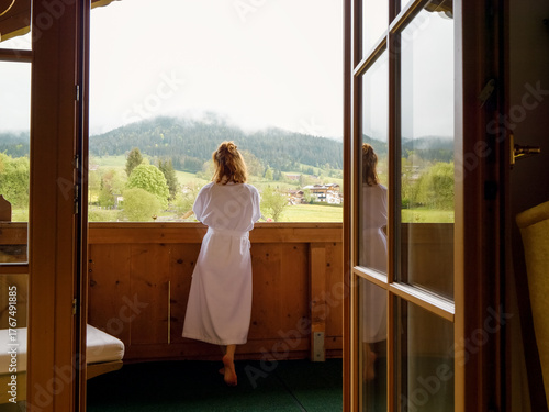 Back view of tourist female enjoying the mountain view from her room. Paradise vacation relaxation with beautiful overview to the mounts.