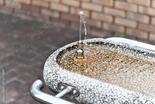 Photography 公園や公共スペースにある石造りの水飲み場：水しぶきが涼しげな噴水と蛇口。喉の渇きを潤す、休憩、リフレッシュ、都市の日常、清潔感を伝えるイメージ素材。