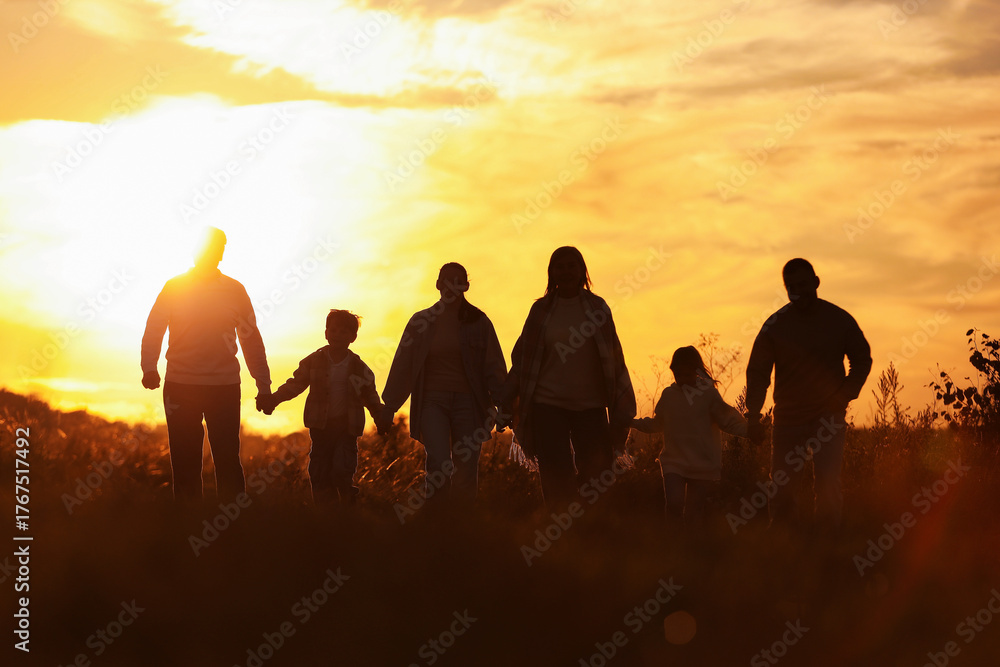 Fototapeta premium Family holding hands in field at sunset