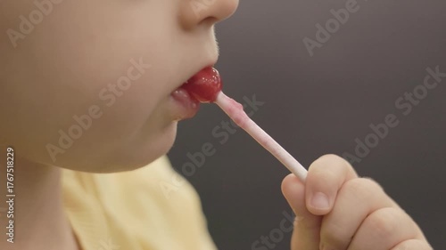 Child enjoying sweet lollipop and licking candy stick