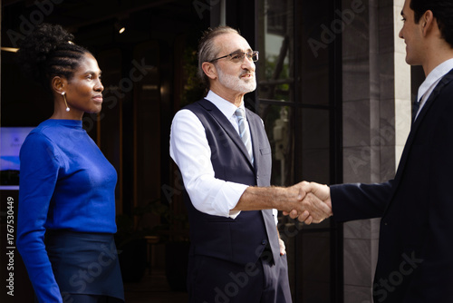 Happy senior elderly businessman has handshake for greeting with business partner in front of office building. Successful officer worker shaking hands after finish deal outside. Cheerful business team