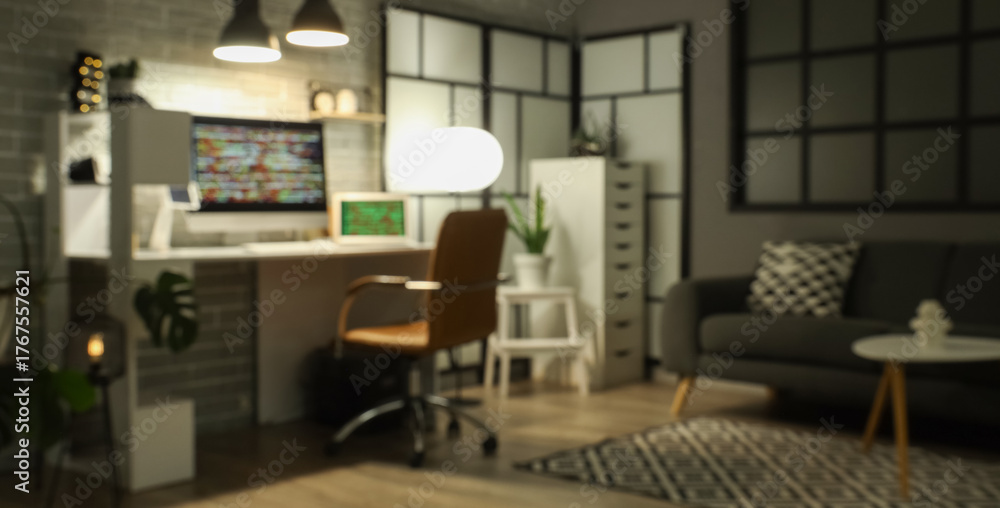 Fototapeta premium Blurred view of dark programmer's office with workplace, sofa and glowing lamps at night