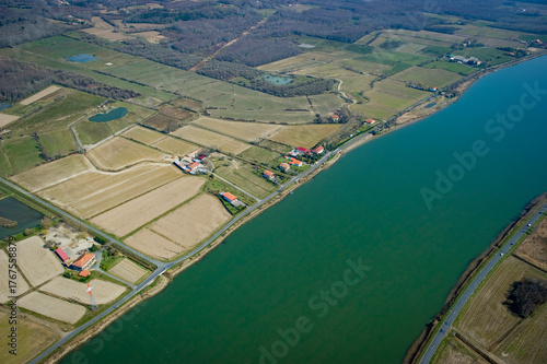 This captivating view showcases the Adour river winding through Urt, Landes. Surrounding farmland and peaceful homes highlight the natural beauty of the area, inviting exploration.