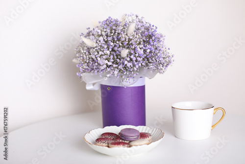 
Cup of tea and berry macarons, bouquet of violet flowers