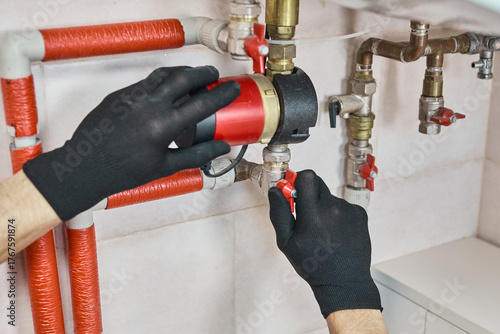 Plumber hands installing circulation pump for a heating system, connecting pipes and control valves