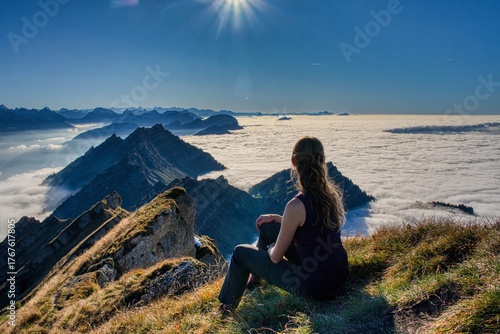 A young woman on the Speer mountain enjoys the view of the sea of ​​fog and the surrounding mountains. Hiking in Switzerland. Near Glarus and Toggenburg. High quality photo.