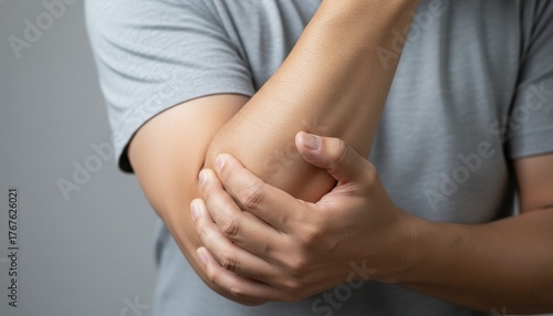 Elbow Discomfort: A person's hand grips their elbow, their facial expressions reveal the pain and discomfort they feel