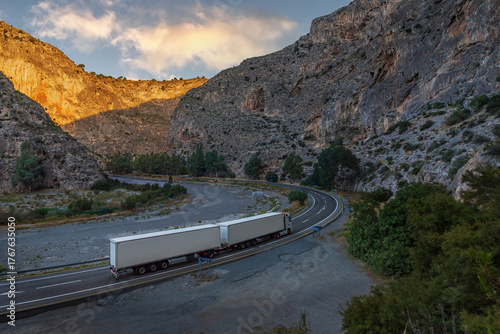 Duo-trailer truck (Long combination vehicle) navigating a serpentine mountain road inside a deep canyon