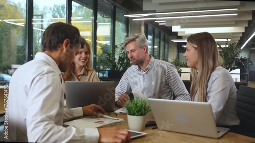 Business people discussing work together using a tablet and laptop taking notes in a modern office
