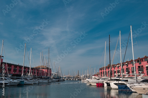 harbor with sailing ships and lighthouse of Genoa in Italy under blue sky