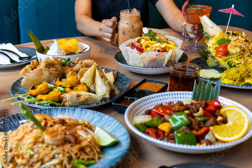 Tableau sur toile Colorful Thai Food Spread with Drinks and Shared Dishes on Restaurant Table