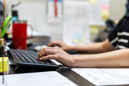 Office Employee Typing on Keyboard with Documents on Desk