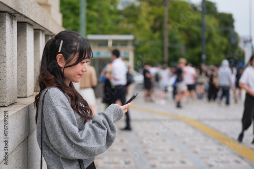 Young woman looking at smartphone on a sidewalk