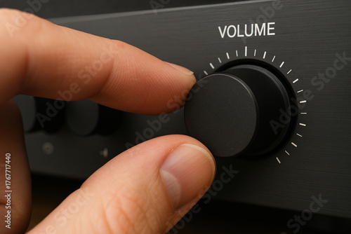Fingers turning a volume control dial on a stereo amplifier