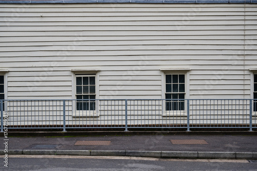White wall with bottom windows and fence separating street