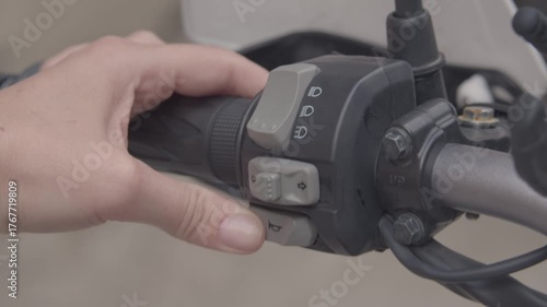 A girl on a motorcycle. A girl sits on an adventure motorcycle during the day, holding the handlebars with bare hands and pressing various buttons: lights, turn signals, horn.