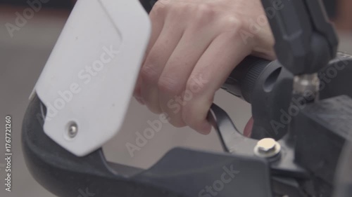 A girl on a motorcycle. A girl sits on an adventure motorcycle during the day, she holds the steering wheel with her bare hands and presses the front brake lever.