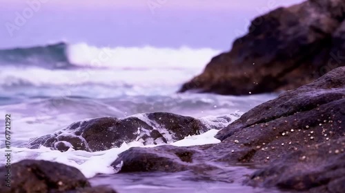 Ocean Waves Crashing On Rocky Shoreline During Soft Evening Light With Purple Hues