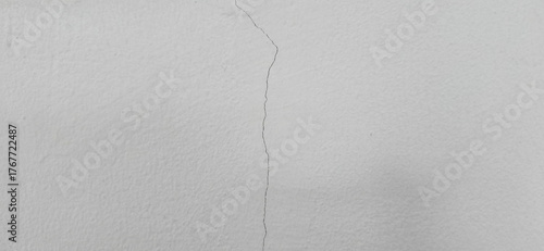 The grey wall has cracks. External cracks in the building. Cracks on the wall are straight lines from the vertical direction. Building problems and solutions. Damage from subsidence, vibration.
